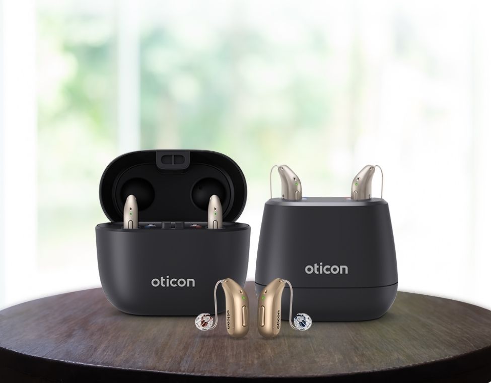 Zwei Oticon Intent Hörgeräte in eleganter Ladebox – leistungsstark, wiederaufladbar und optimal für beidseitiges Hören.