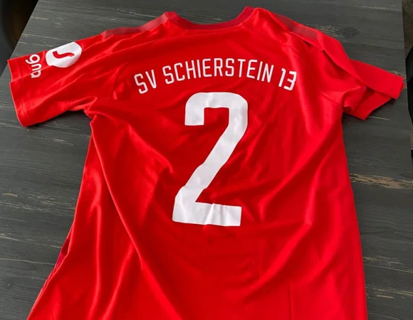 Rückseite des SV Schierstein 13 Trikots mit weißer Rückennummer und Vereinsname auf rotem Stoff.